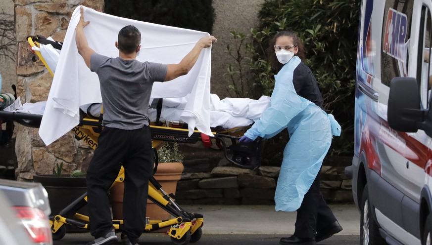 A staff member blocks the view as a person is taken by a stretcher to a waiting ambulance from a nursing facility where more than 50 people are sick and being tested for the COVID-19 virus, Saturday,  ...