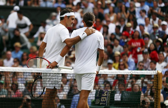 epa06065913 Roger Federer of Switzerland (L) at the net with Alexandr Dolgopolov of Ukraine who retired in their first round match during the Wimbledon Championships at the All England Lawn Tennis Clu ...