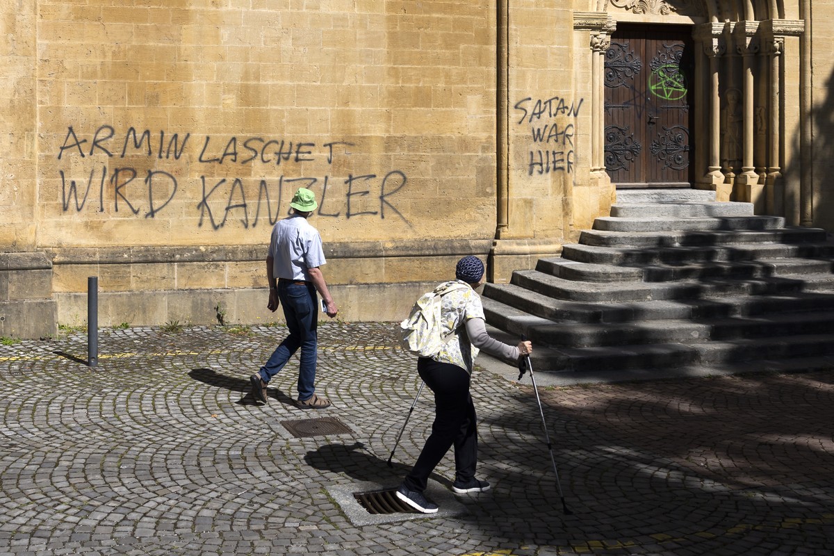 Besucher schauen auf Sprayereien an einer Wand der Kollegiatkirche Neuenburg (Collegiale de Neuchatel) an, am Dienstag, 5. August 2025 in Neuchatel. (KEYSTONE/Peter Klaunzer)