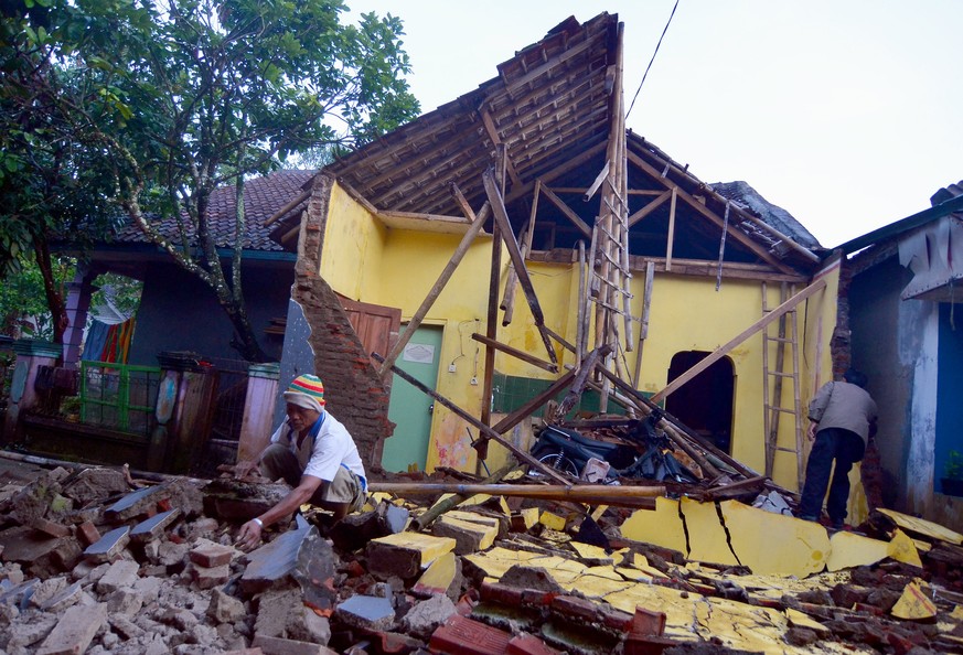 epa06392590 An Indonesian man inspects his property among the ruins of a collapsed house after a 6.5 magnitude earthquake hit Sumelap Village, Tasikmalaya, West Java, Indonesia, 16 December 2017. Acco ...