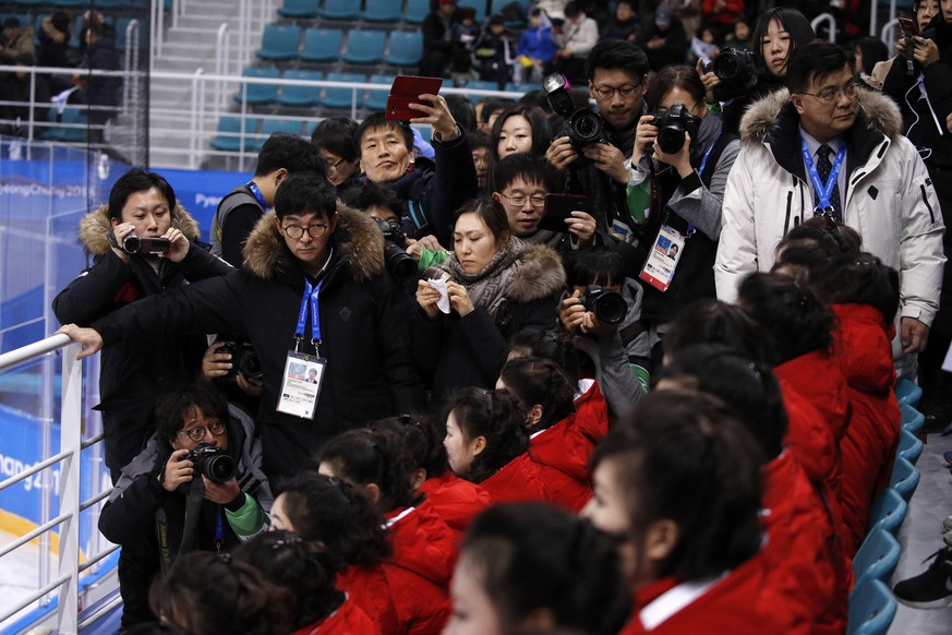 Journalists gather near as North Korean supporters arrive before the preliminary round of the women&#039;s hockey game between Switzerland and the combined Koreas at the 2018 Winter Olympics in Gangne ...