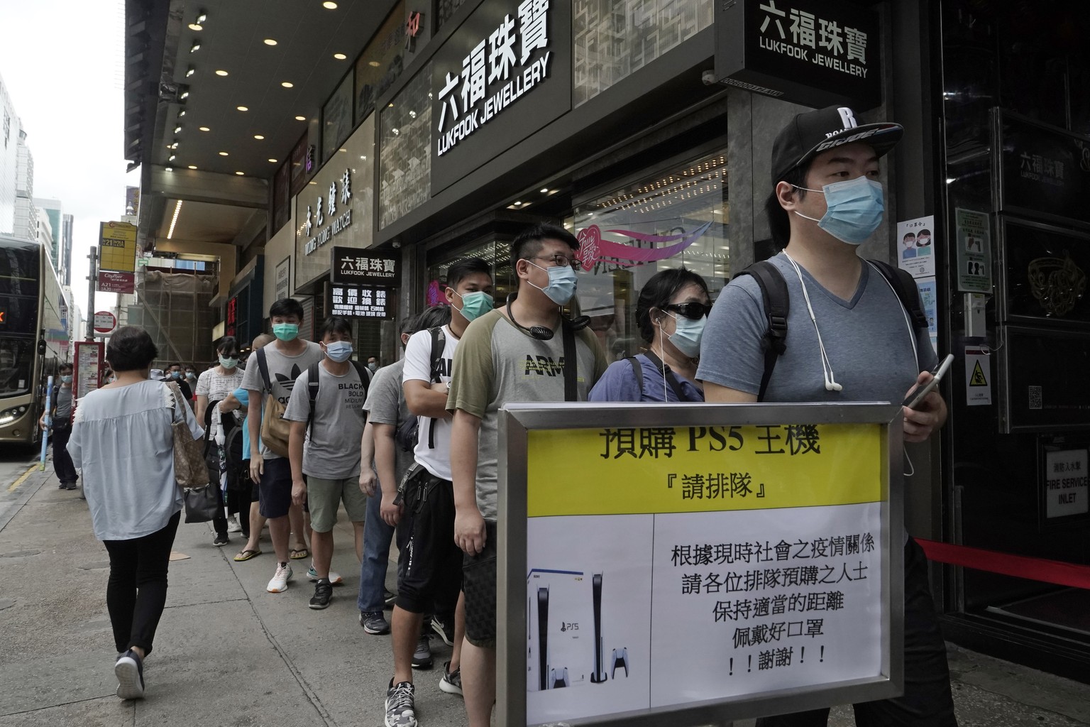 Gaming enthusiasts queue up for the pre-order sales of the newly unveiled Japanese brand video game console, Sony&#039;s PlayStation 5 (PS5), outside a retailer in Hong Kong, Friday, Sept. 18, 2020. P ...