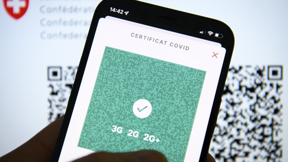 Une personne tient dans sa main un smartphone avec l&#039;application Certificat Covid suisse et son code QR indiquant 3G, 2G et 2G+ ce mercredi 12 janvier 2022 a Lausanne. (KEYSTONE/Laurent Gillieron ...