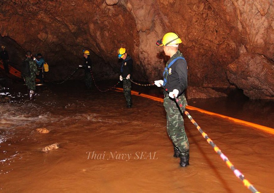 epa06866883 A handout photo made available by the Thai Navy SEAL on 06 July 2018 shows Thai military personnel carrying equipment inside a cave complex during the ongoing rescue operations for the you ...