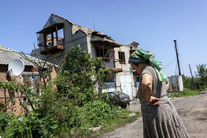 Eine Frau steht vor den Ruinen eines Hauses in der Nähe von Slawiansk.