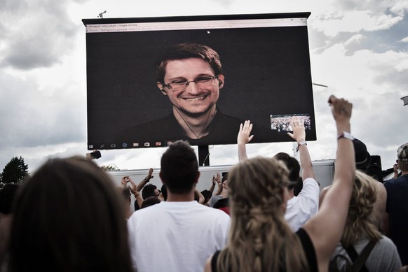 epa05396764 Festival-goers greet whistleblower Edward Snowden (on screen) during a via live stream interview with The Yes Men during Roskilde Festival in Roskilde, Denmark, 28 June 2016. The festival  ...