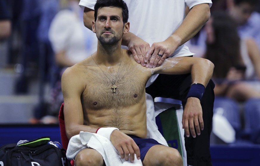 Novak Djokovic, of Serbia, receives treatment from a trainer during his match against Juan Ignacio Londero, of Argentina, during the second round of the U.S. Open tennis tournament in New York, Wednes ...