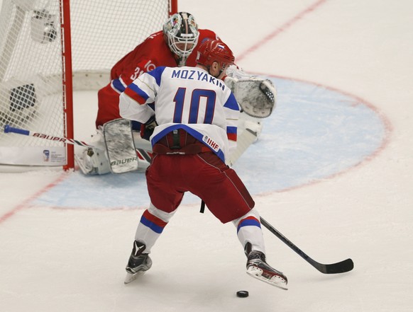 Russiaâs Sergei Mozyakin, foreground, takes a shot at goal as Norwayâs goalkeeper Lars Volden, background tries to block him during the Hockey World Championships Group B match in Ostrava, Czech R ...