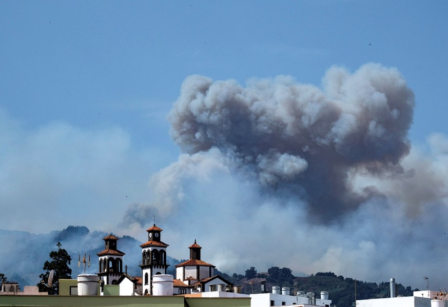 epa07779216 Smoke rises from a forest fire that continues to burn land in Moya, Gran Canaria, Canary Islands, Spain, 18 August 2019. About 2,000 people have been evacuated from the area due to a fores ...