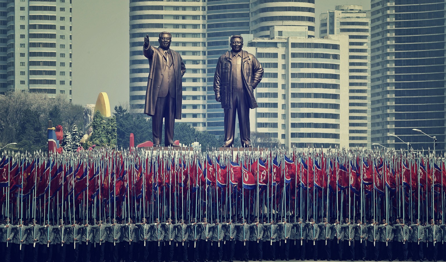 Universitätsstudenten tragen nordkoreanische Fahnen unter Bronzestatuen der verstorbenen Führer Kim Il-sung und Kim Jong-il, Pjöngjang, 2017.