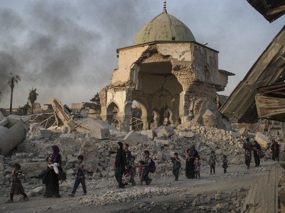 Fleeing Iraqi civilians walk past the heavily damaged al-Nuri mosque as Iraqi forces continue their advance against Islamic State militants in the Old City of Mosul, Iraq, Tuesday, July 4, 2017. Islam ...
