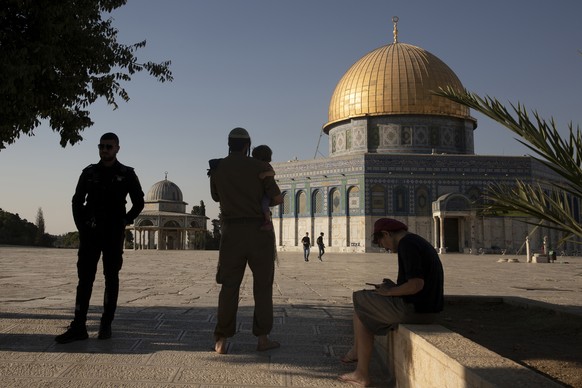 An Israeli police officer stands guard as a religious Jew in Army uniform visits the Temple Mount, known to Muslims as the Noble Sanctuary, on the Al-Aqsa Mosque compound in the Old City of Jerusalem, ...