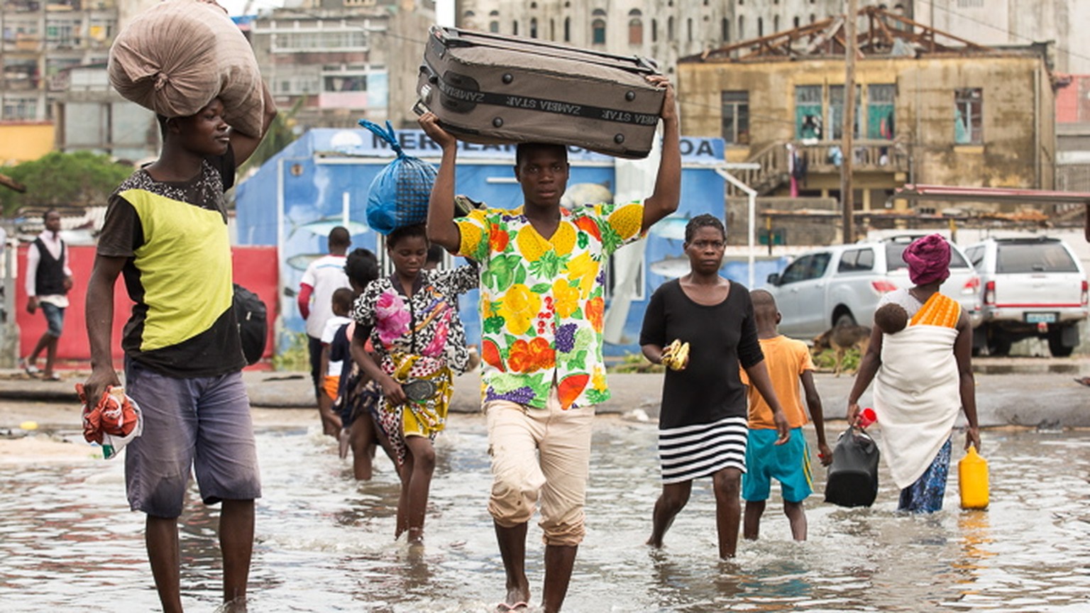 epa07447732 A handout photo made available by the International Federation of Red Cross (IFRC) showing people carry their persinal effects through a flooded section of Praia Nova, Beira, Mozambique, a ...