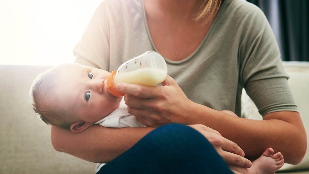 Babynahrung, Baby, Milch, Babymilch, Flasche, Nestlé, Hochdorf, Mom, milk and feeding baby in living room for growth development, nutrition or digestive health. Lens flare, formula and woman with infa ...
