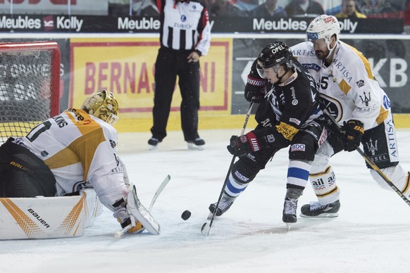 Fribourgs Nathan Marchon, Mitte, im Duell mit Luganos Goalie Elvis Merzlikins, links, und Thomas Wellinger im Eishockey Meisterschaftsspiel der National League zwischen dem HC Fribourg-Gotteron und de ...