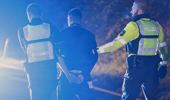 30.11.2024, Nordrhein-Westfalen, Hagen: Polizisten nehmen einen Lastwagenfahrer (M) auf der Autobahn 1 bei Hagen in Gewahrsam. Bei der Chaosfahrt eines Lastwagens �ber mehrere Autobahnen in Nordrhein- ...