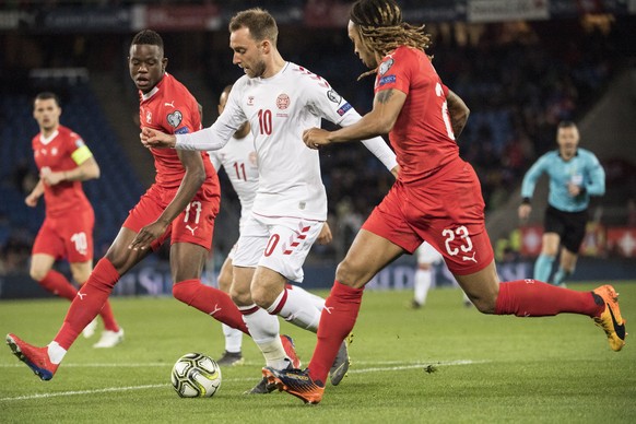 epa07465481 Swiss Denis Zakaria, left, and Kevin Mbabu, right, fight against Denmark&#039;s Christian Eriksen (C) during the UEFA Euro 2020 qualifying Group D soccer match between Switzerland and Denm ...