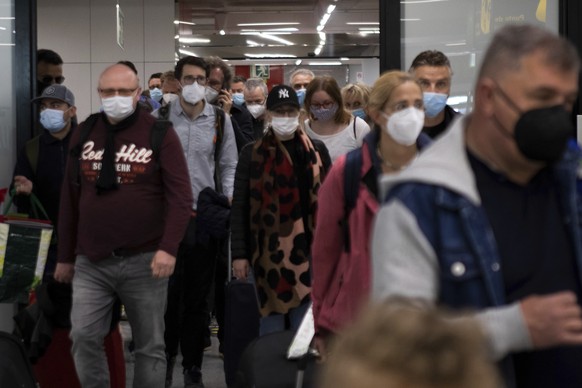 Passengers wearing face masks arrive at Palma de Mallorca Airport on the Spanish Balearic Island of Mallorca, Spain, Saturday, March 27, 2021. Efforts in Spain to restart tourism activity is drawing a mixed picture due to a patchwork of national, regional and European rules on travel that is confusing both tourists and their hosts. (AP Photo/Francisco Ubilla)