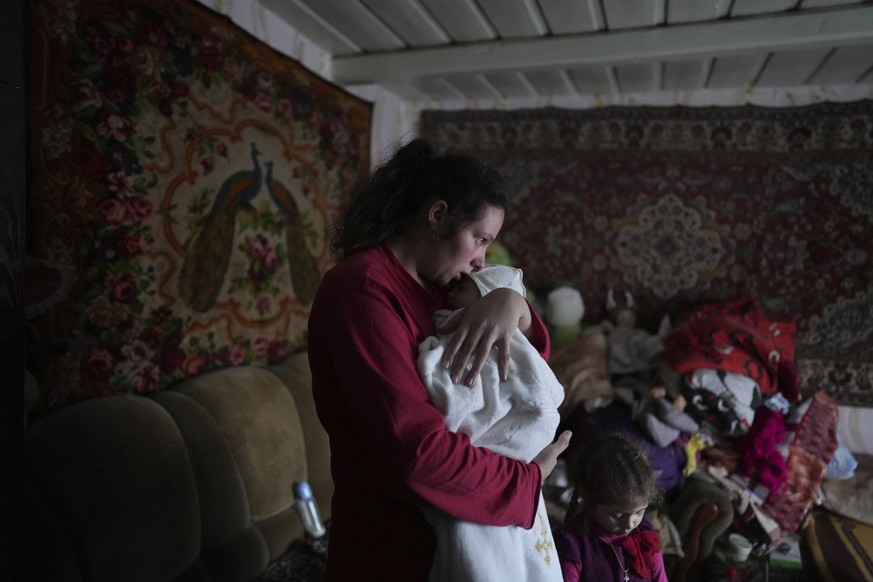 Anastasia Manha, 23, lulls her 2-month-old son Mykyta, where she lives with her family members, after shelling by separatists forces in Novognativka, eastern Ukraine, Sunday, Feb. 20, 2022. (AP Photo/ ...