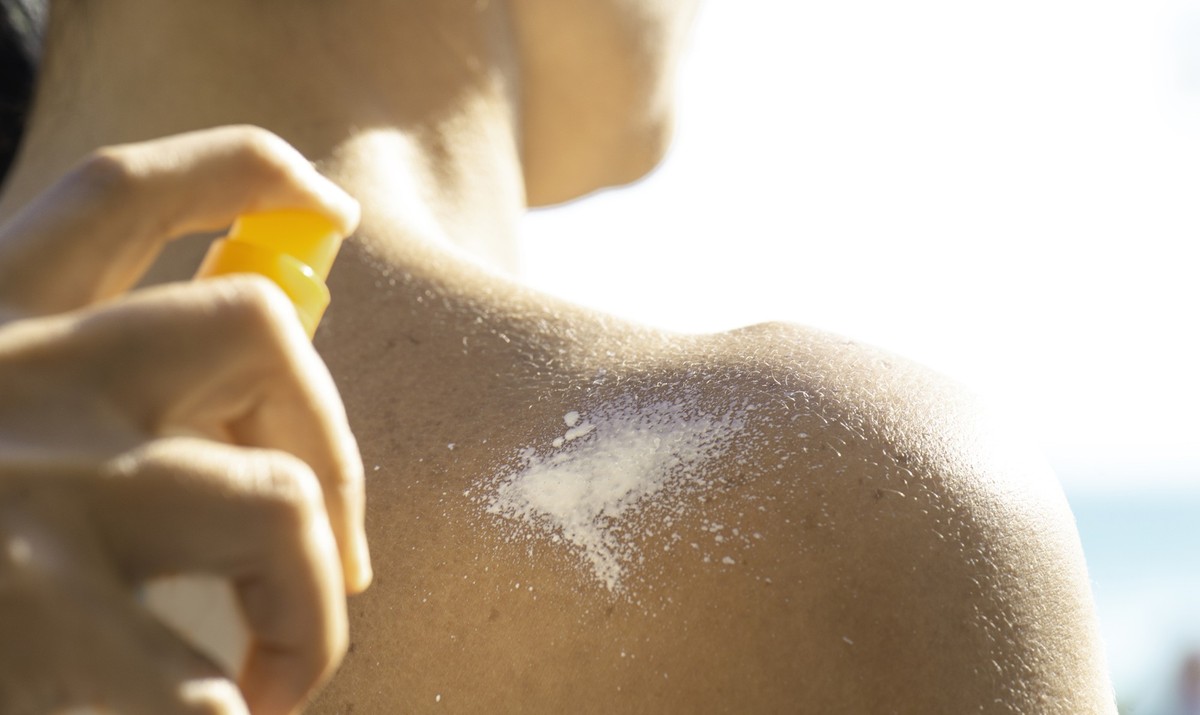 Mann wird eingecremt mit Sonnencreme-Spray