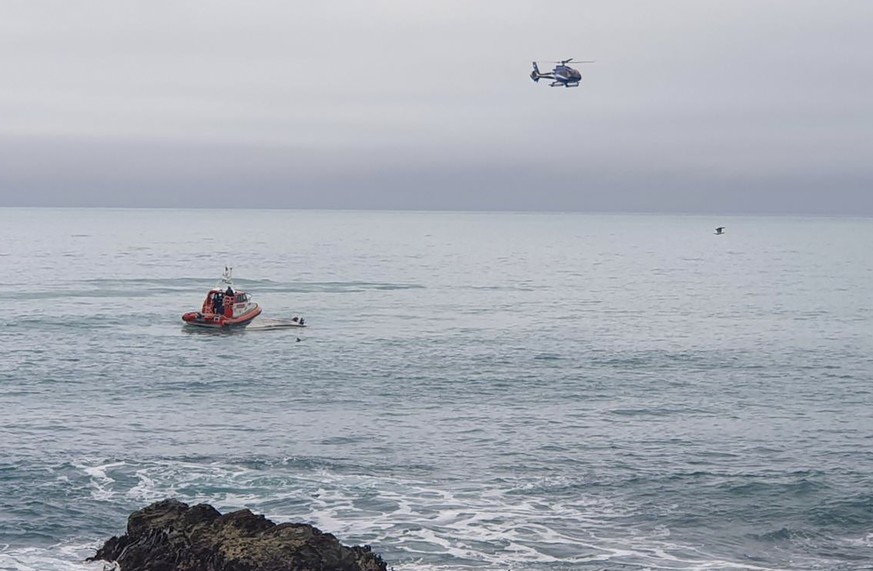 A helicopter and a rescue boat search for survivors off the coast of Kaikoura, New Zealand, Saturday, Sept. 10, 2022. A boat in New Zealand collided with a whale and capsized. (AP Photo)