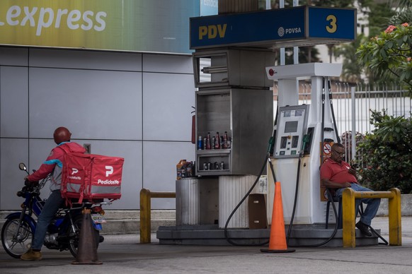 epa10778855 An attendant (R) waits for customers at a gas station in Caracas, Venezuela, 27 July 2023 (issued 31 July 2023). The goose that lays the golden eggs of Venezuela, the oil industry, has bee ...