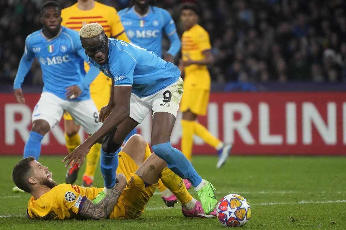 Napoli's Victor Osimhen, top, and Barcelona's Inigo Martinez, bottom, challenge for the ball during the Champions League, round of 16, first leg soccer match between SSC Napoli and FC Barcel ...