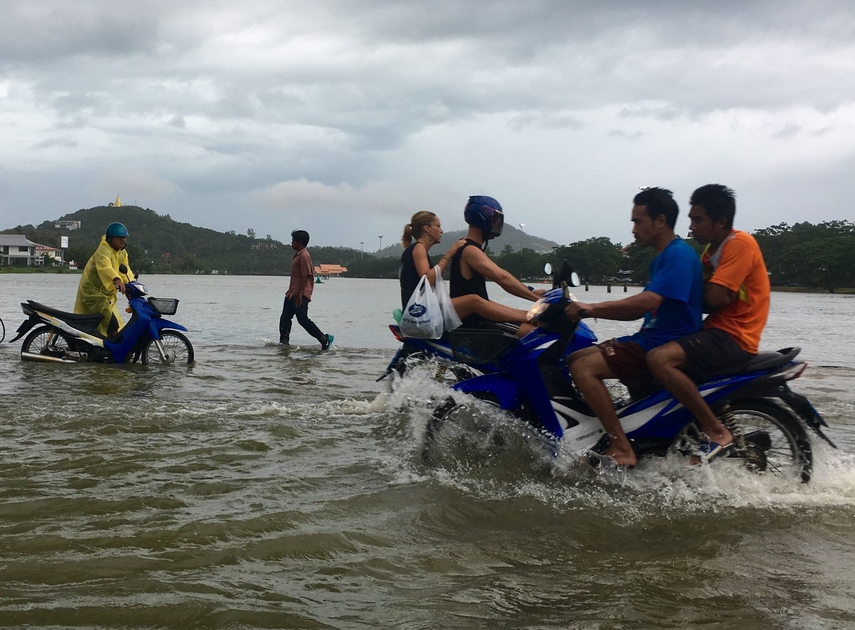 Riders use a road flooded by an overflowing lake on Ko Samui, Thailand Thursday, Jan. 5, 2017. Heavy rains battering parts of Thailand are causing localized flooding on the resort island during a peak ...
