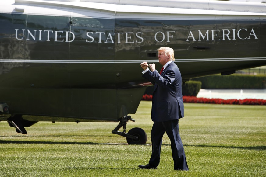 President Donald Trump reacts on seeing visitors to the White House as he walks on the South Lawn of the White House in Washington, Friday, Aug. 4, 2017, to board Marine One helicopter for a short tri ...