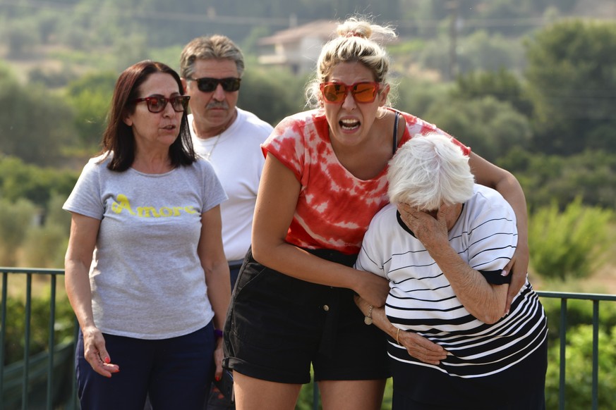 Local residents react during a wildfire near Olympia town, western Greece, Thursday, Aug. 5, 2021. Wildfires rekindled outside Athens and forced more evacuations around southern Greece Thursday as wea ...