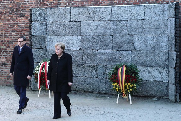 epa08048629 German Chancellor Angela Merkel (R) and Polish Prime Minister Mateusz Morawiecki (L) lay a wreath at the Death Wall during a visit to the Auschwitz-Birkenau Memorial and Museum of former N ...