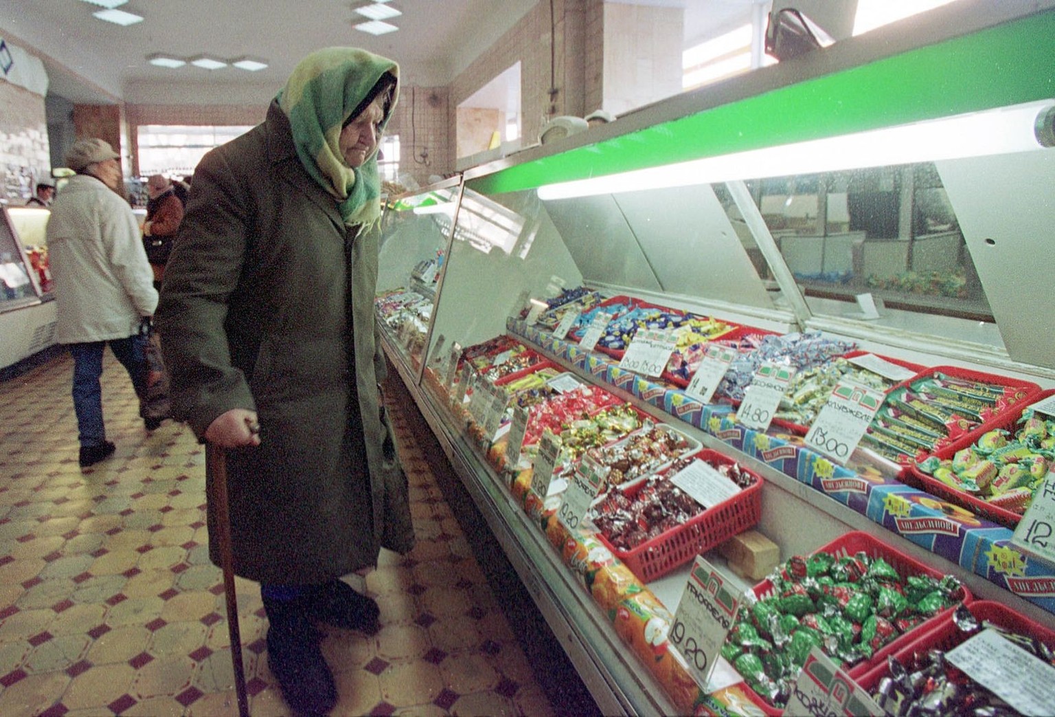 An eldery Ukrainian woman looks at candies at the confectionery department of Kiev supermarket, Ukraine, on Friday, March 3, 2000. Most Ukrainian pensioners can hardly survive for a monthly pension of ...