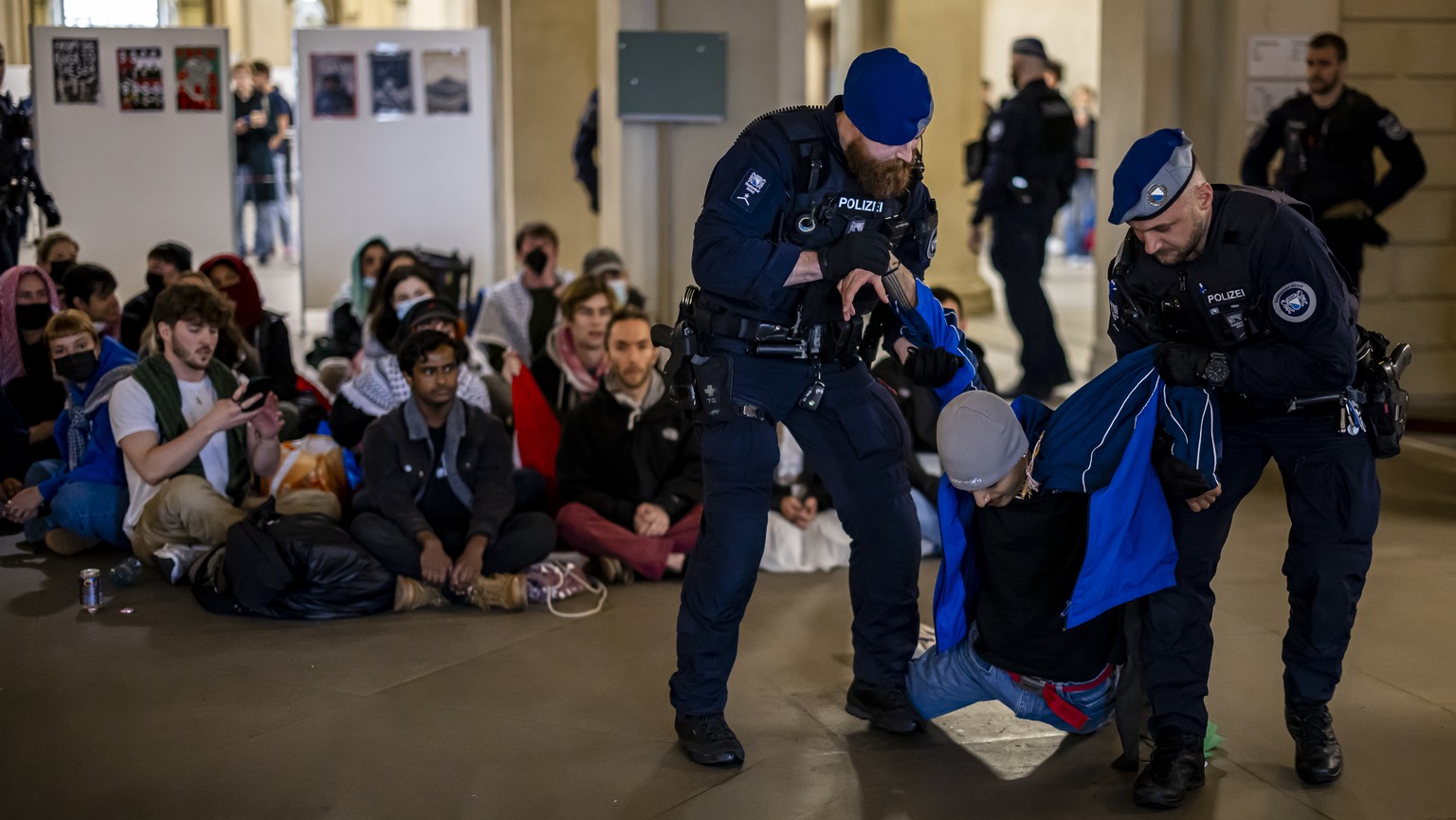Police officers carry away a Pro-Palestinian demonstrator during protest in the entrance hall of the main building of the ETH Zurich on Tuesday, May 7, 2024 in Zurich, Switzerland. (KEYSTONE/Michael B ...