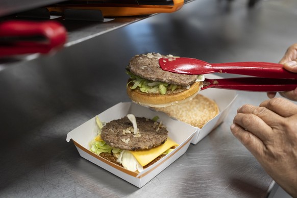 Ein Mitarbeiter eines McDonald's-Restaurants stellt in der Kueche aus verschiedenen Zutaten einen Burger mit Rindfleisch zusammen, fotografiert am Dienstag, 19. Mai 2026 im Autobahnzentrum Fuchsb ...