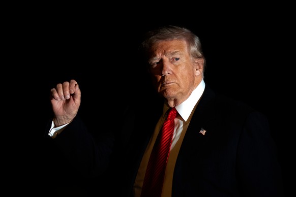 FILE - President Donald Trump is illuminated by a camera flash as he gestures while walking across the South Lawn of the White House, Nov. 2, 2025, in Washington, after returning from a trip to Florid ...