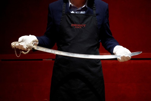 A Drouot employee holds the saber that Napoleon ordered for his personal use from the arquebusier Nicolas-Noel Boutet in 1802 before its auction at Drouot auction house in Paris, France, April 24, 202 ...