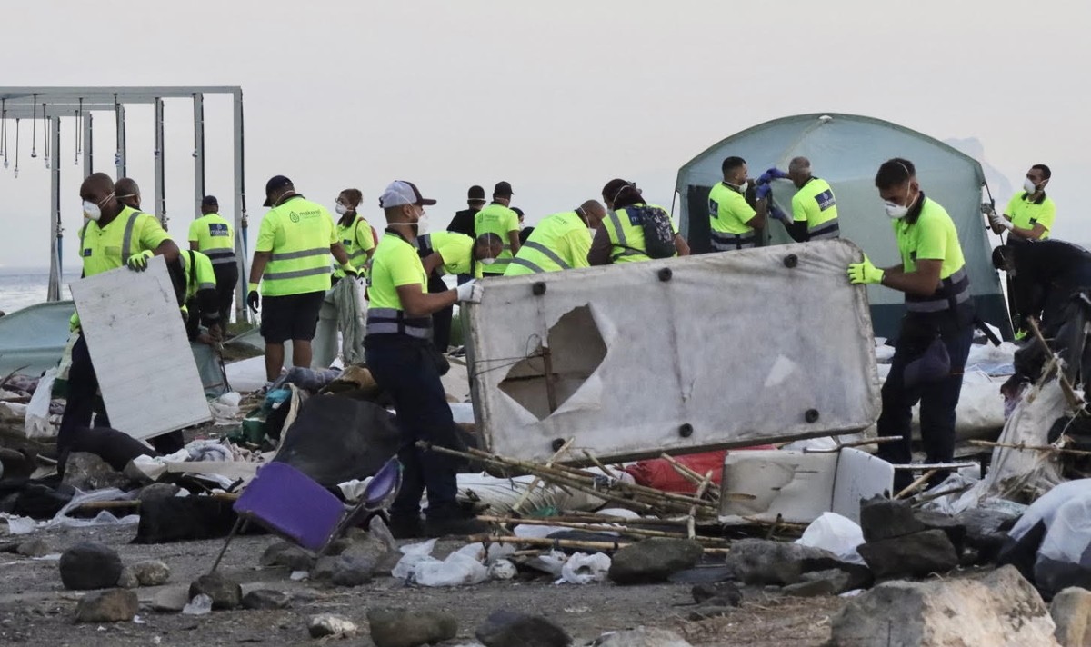 epa13295935 Workers of the 'Makerel' cleaning company remove waste and debris during the eviction of migrants from a migrant camp set up in the esplanade in front of the old El Guano factory ...