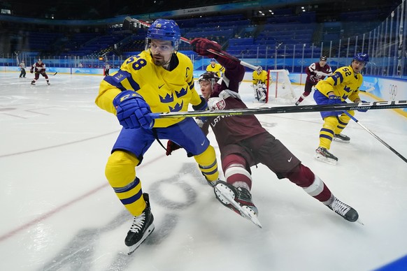 Sweden&#039;s Anton Lander (58) and Latvia&#039;s Ronalds Kenins (91) battle in the corner during a preliminary round men&#039;s hockey game at the 2022 Winter Olympics, Thursday, Feb. 10, 2022, in Be ...