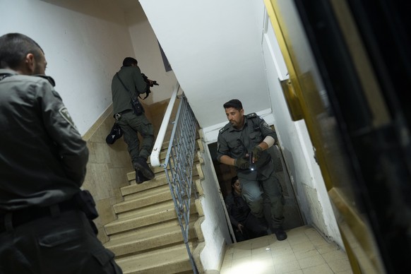 Israeli police officers run upstairs as they search for a suspect in a shooting attack in Tel Aviv, Israel, Thursday, March 9, 2023. Israeli police said a Palestinian gunman shot and wounded three peo ...