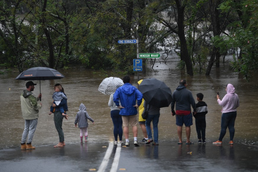 epa09089237 Onlookers watch the submerged New Windsor Bridge at Windsor in the north west of Sydney, Australia, 22 March 2021. Thousands of residents are fleeing their homes as schools are shut, and s ...