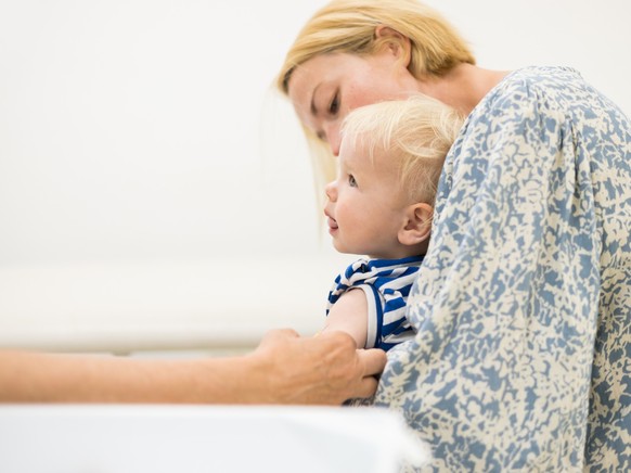 child beeing vaccinated by pediatrician in presence of his mother. Preventive vaccination against Diphtheria, whooping cough, tetanus, hepatitis, haemophilus influenzae, pneumococcus, poliomyelitis. M ...