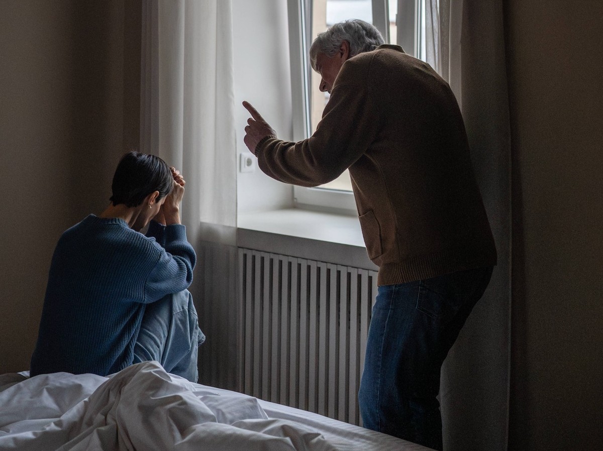 Häusliche verbale Gewalt und Missbrauch, erschöpfte Frau wird von gereiztem Mann verbal angegriffen. Domestic verbal violence and abuse, stressed mature woman hiding from yelling frustrated husband, e ...