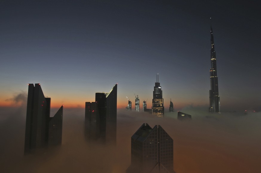 The sun rises over the city skyline with the Burj Khalifa, world&#039;s tallest building at the backdrop, seen from a balcony on the 42nd floor of a hotel on a foggy day in Dubai, United Arab Emirates ...