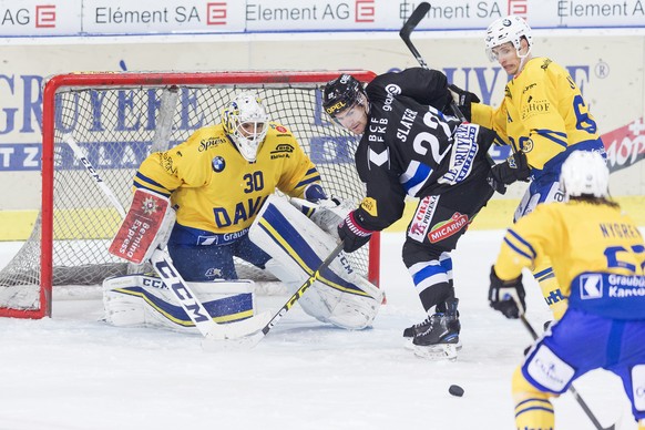 Le gardien davosiens Joren van Pottelberghe, gauche, lutte pour le puck avec l&#039;attaquant fribourgeois Jim Slater, centre, lors du match du championnat suisse de hockey sur glace de National Leagu ...