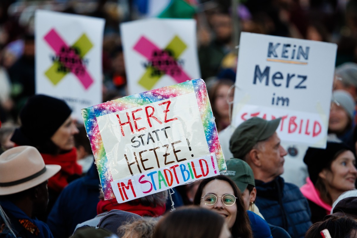 epa12465383 A participant holds a placard that reads 'Heart instead of agitation in the cityscape' during a rally at the Brandenburg Gate landmark in Berlin, Germany, 19 October 2025. The ra ...