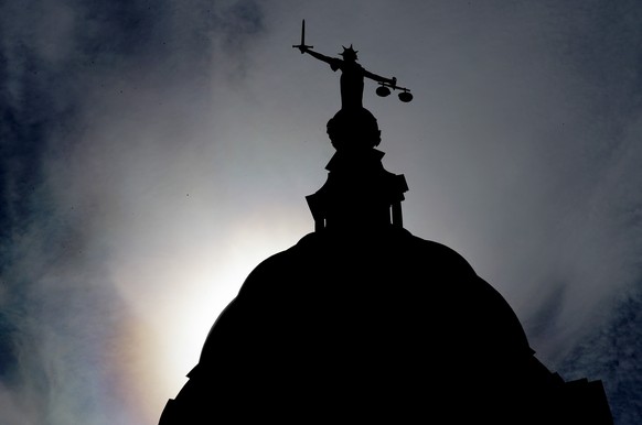 FILE - A statue of liberty is silhouetted as it stands atop the Old Bailey, Central Criminal Court, in London, Thursday, Aug. 8, 2019. A British judge has jailed for life a man who killed his grandfat ...