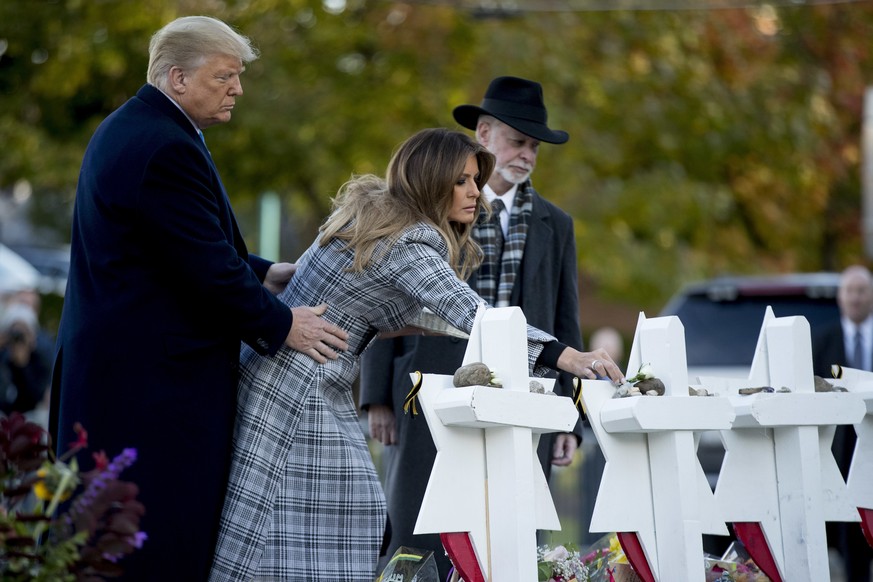 First lady Melania Trump, accompanied by President Donald Trump, and Tree of Life Rabbi Jeffrey Myers, right, puts down a white flower at a memorial for those killed at the Tree of Life Synagogue in P ...