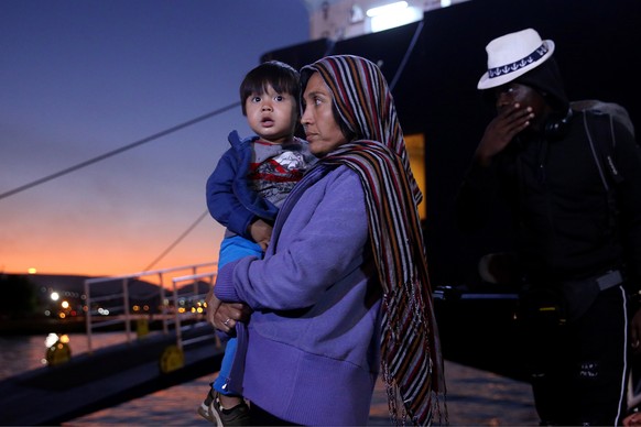 epa07884462 A refugee carries her child as she disembarks from the ferry &#039;Nissos Rodos&#039; which arrived from Lesvos island at the port of Piraeus, Greece, 01 October 2019. The ship arrived at  ...