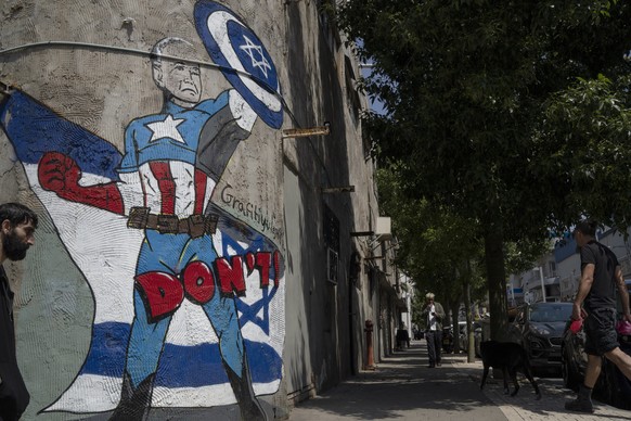 A man walks past a mural depicting the U.S. president Joe Biden as a superhero defending Israel on a street in Tel Aviv, Israel, Sunday, April 14, 2024. Israel on Sunday hailed its successful air defe ...