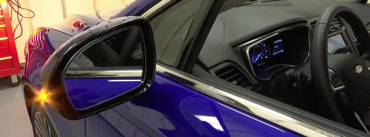 In this Aug. 16, 2016, image taken from video, a light flashes on the side mirror of a Ford sedan in Dearborn, Mich., after the driver activated the vehicle's four-way flashers. The indicator is  ...